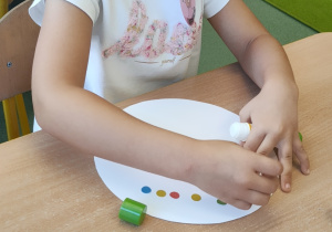 Dziewczynka siedzi przy stoliku i wykonuje pracę plastyczną