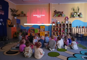 dzieci oglądają na dywanie projekcję bajki