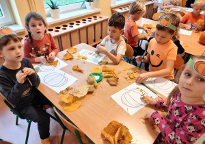 dzieci naklejają liście na dynie