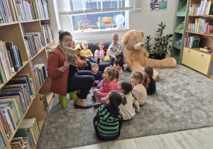 Pani bibliotekarka pokazuje dzieciom ilustracje w książce