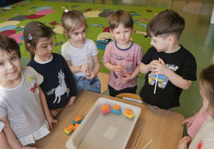 Dzieci stoją wokół pojemnika z wodą.