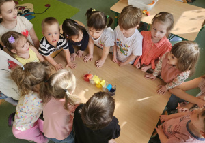 Dzieci stoją i obserwują jak zabarwiają się chusteczki.