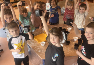 Dzieci pokazują swoje doniczki wraz zasianą rzeżuchą.