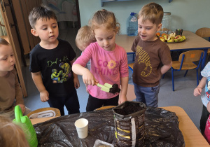 dziewczynka wsypuje ziemię do kubeczka