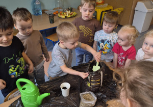 chłopiec wsypuje ziemię do kubeczka