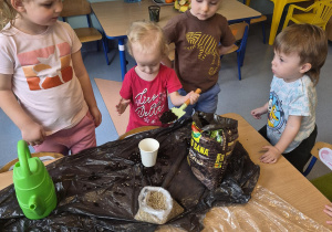 dziewczynka wsypuje ziemię do kubeczka