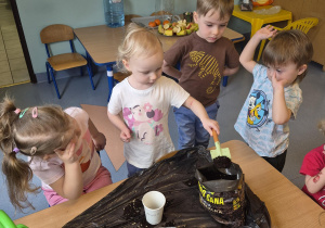 dziewczynka wsypuje ziemię do kubeczka