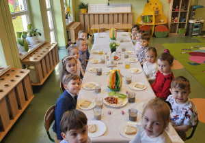 Dzieci siedzą przy przystrojonym stole.