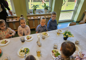 Dzieci siedzą przy wielkanocnym stole.