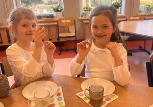 Dziewczynki stukają sie czekoladowymi jajeczkami.