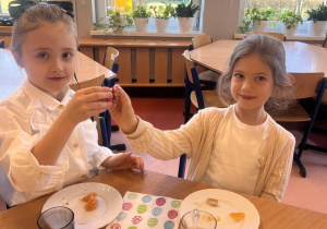 Dziewczynki stukają się czekoladowymi jajeczkami.