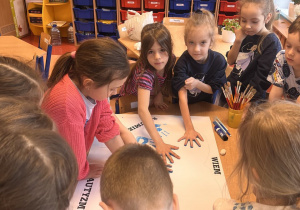 Dzieci odbijają dłoń na papierze .