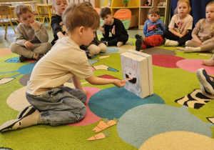 Chłopiec symbolicznie karmi królika marchewkami.