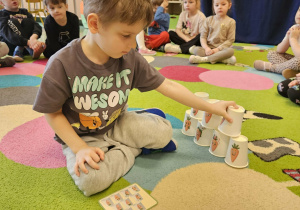 Dziecko układa kubki według wzoru.