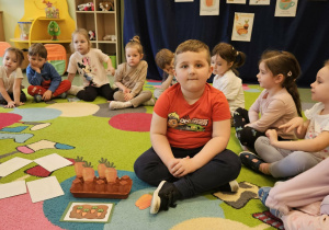 Chłopiec siedzi obok pudełeczka z marchewkami.