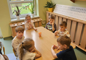 Dzieci siedzą i chrupią marchewkę.