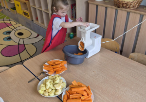 dziewczynka ściera jabłka i marchewki