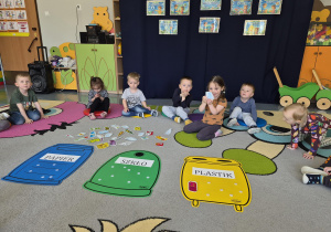 dzieci segregują śmieci do odpowiednich pojemników