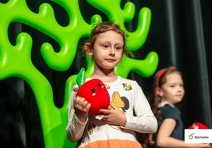 Zuzia pozuje z maskotką -jabłko.