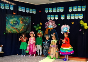 Dzieci stoją na tle dekoracji.