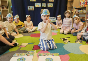 Dzieci siedzą w kole i segregują obrazki.