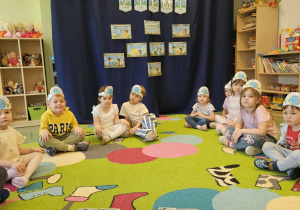 Dzieci siedzą na tle dekoracji.