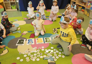 Dzieci siedzą w kole, a dwójka na środku układa obrazki.