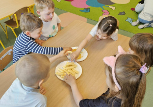 Przedszkolaki moczą chrupki w miodzie.