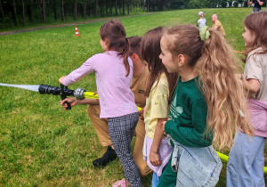 Dzieci leją wodą z węża strażackiego