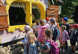 Dzieci oglądają domek z postaciami z bajki.