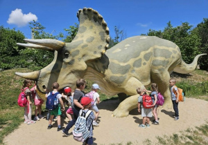Dzieci dotykają dinozaura.