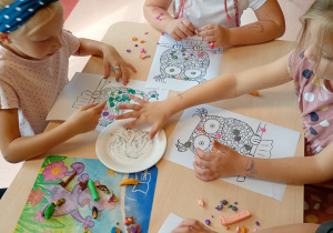 dzieci przy stoliku wykonują pracę plastyczną
