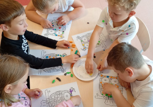 dzieci przy stoliku wykonują pracę plastyczną