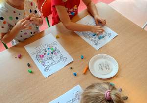 dzieci przy stoliku wykonują pracę plastyczną