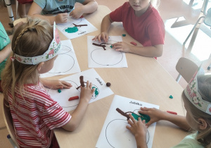 dzieci przy stoliku wykonują pracę plastyczną