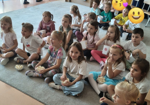 dzieci jedzą popcorn