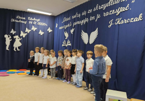 Dzieci stoją przed dekoracją i śpiewają piosenkę.