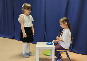 Dziewczynki odgrywają scenkę przy granatowym materiale.