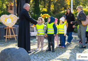 Dzieci pod pomnikiem z księdzem.