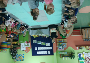 Dzieci siedzą w półkolu z nauczycielką - herbaciarką.