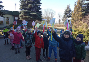 Dzieci z wiosennymi symbolami i emblematami przez budynkiem przedszkola