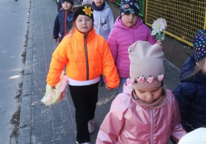 Dzieci z emblematami wiosennymi idą w wiosennym korowodzie.