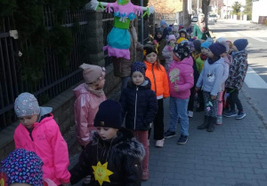 Dzieci z emblematami wiosennymi idą w wiosennym korowodzie.