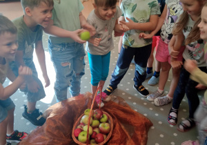 dzieci podają sobie jabłko