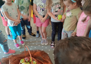 dzieci podają sobie jabłko