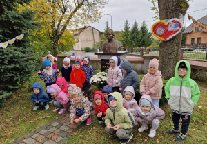 Dzieci pozują do zdjęcia przy popiersiu Jana Pawła II