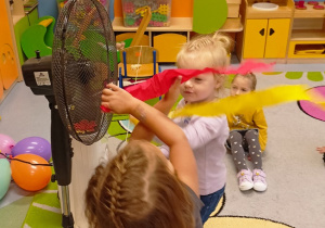 dzieci obserwują jak zachowuje się bibuła gdy dmucha na nią powietrze z wiatraka