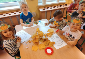 dzieci dekorują dynię liśćmi
