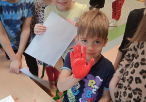 chłopiec robi odcisk pomalowanej dłoni
