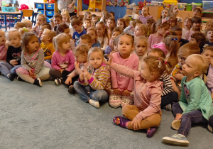 Zgromadzone dzieci siedzą na dywanie podczas spotkania z Górnikiem